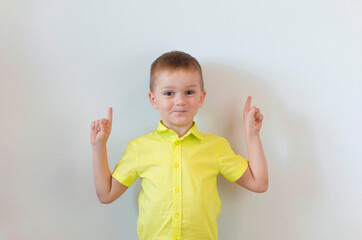 A boy on a white background shows his thumbs up. Copy space