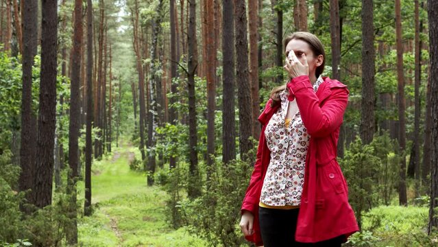 Person practicing EFT in nature forest. Female tapping karate chop, eyebrow, side of the eye, under the nose and chin points.