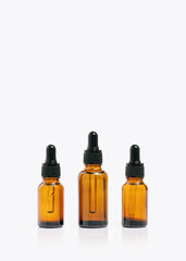 Natural medicine or essential aroma oil or beauty essence concept three vials bottle with dropper on airy white background. Face and body spa serum care concept banner