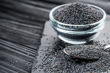 poppy seeds on a black rustic wooden background