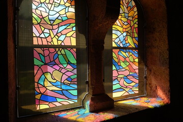 sun shining through colorful stained glass window in church in france making abstract patterns on...