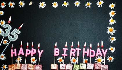 Happy birthday background with number   35. Copy space. Pink happy birthday candles on a black...