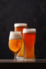 Three different glasses of beer on black background.