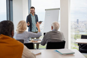 Friendly young teacher is teaching a group of multicultural senior students importance of technology in modern world.