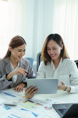 Obraz premium young Asian businesswoman using tablet computers to plan marketing strategies and invest to profit from customers