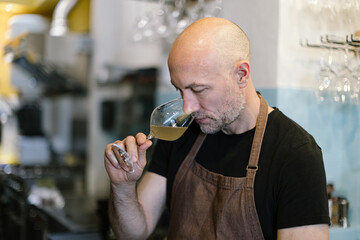 winetaster smelling a white wine - sommelier proving wine - wine bar owner at shop