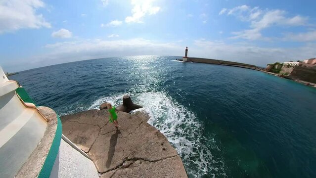 Top view of a tourist woman walking around the lighthouse in the pier of the of Bastia city in Corsica island of France. Aerial view of cityscape with the lighthouse of the city port in Tyrrhenian sea