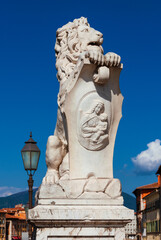 Fototapeta na wymiar Marble lion statue with old streetlamp, erected in 1875 in Pisa historical center