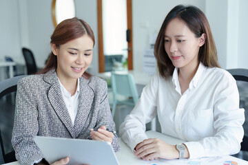 young Asian businesswoman using tablet computers to plan marketing strategies and invest to profit from customers