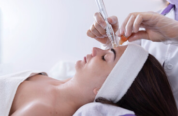 close up of Cosmetologist,beautician applying facial dermapen treatment on face of young woman...