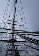 Sailing ship masts and rigging on blue sky background