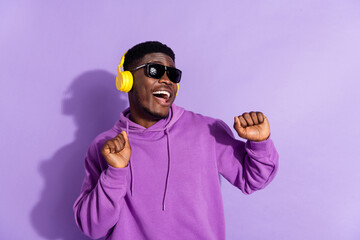 Portrait of overjoyed positive man chilling have good mood favorite playlist isolated on violet...