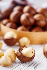 fresh macadamia nuts on a white wooden rustic background