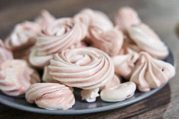 pink meringues on a plate close-up, different sizes, side view