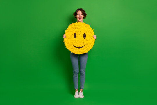 Full length photo of cheerful crazy girl hands hold big smile emoji isolated on green color background