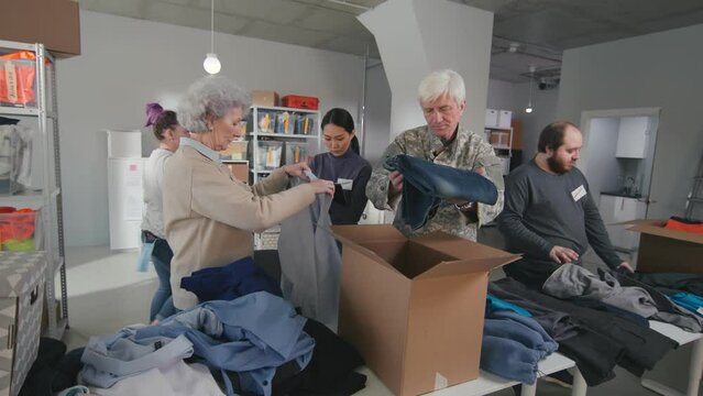 International group of people pack donated clothes at distribution or refugee assistance center