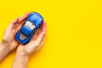 Car insurance concept. Toy car in hands, top view