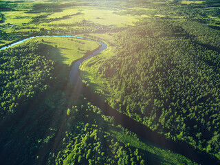 Aerial view road and curved river flowing through the green forest