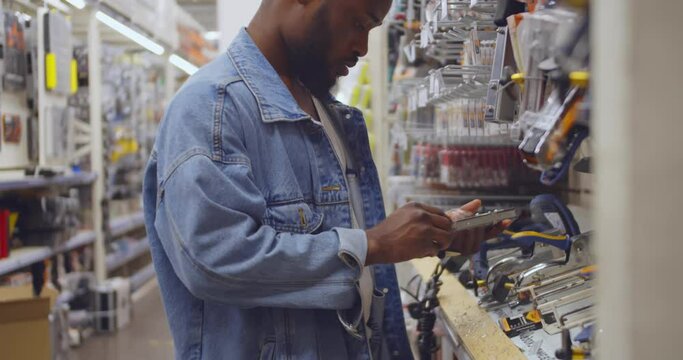African-American man choose staple gun in diy store. Realtime