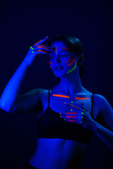 Fototapeta premium Unusual fluorescent makeup on the skin of a beautiful woman, glowing under ultraviolet light.