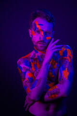 Fashion portrait of a man with ultraviolet paint on his body and neon light in cyberpunk style.