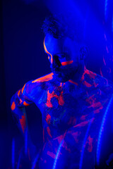 Fototapeta na wymiar Portrait of a man with ultraviolet makeup and neon light in cyberpunk style.