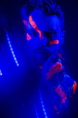 Handsome boy dancing at the rave party with fluorescent paintings on his face
