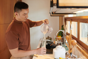 Man filling plastic bottle with protein shake he made for breakfast