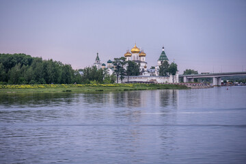 an old white-stone monastery on the banks of the river on a summer day
