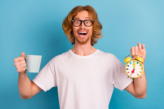 Portrait of excited funky person hold coffee cup retro classic clock isolated on blue color background