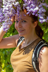 beautiful woman with wisteria flowers next to her face in summer