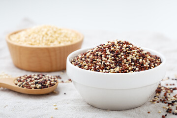 White, red and black quinoa in white bowl on table