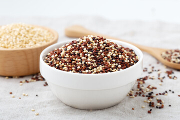 Raw mixed quinoa in white bowl on table