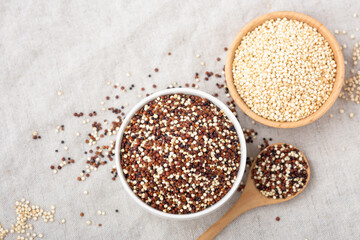 Red ,white and black quinoa in bowls with spoon on table