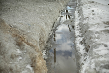 Path in water. Puddle on trail. Melting snow in city.