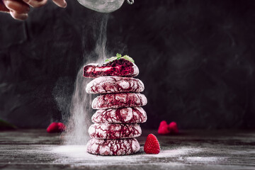 Red velvet cookies. Chefs hands with small sieve for baking sprinkling powdered sugar. Baker...