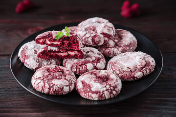 Crispy biscuits on black plate. Cookies Red velvet with cream filling. Half of broken cookie and whole cookies decorated powdered sugar, holiday baking recipe, colorful food, homamed bakery.