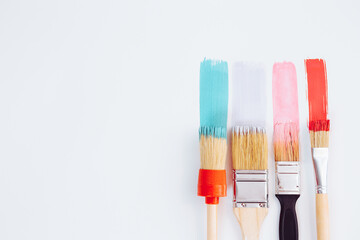 Artistic background. Paintbrushes are painting colorful brushstrokes on light background. Trendy...