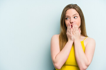 Young caucasian woman isolated on blue background thoughtful looking to a copy space covering mouth with hand.