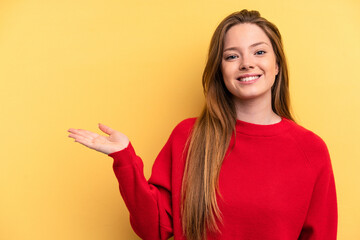 Young caucasian woman isolated on yellow background showing a copy space on a palm and holding another hand on waist.