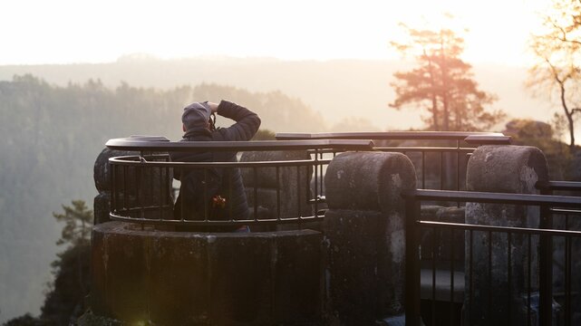 Back shot of a tourist standing at the viewpoint of the Basti rocks taking photos of the nature