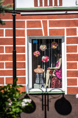 window with a doll on the windowsill of a red brick house