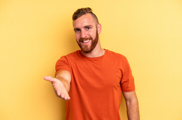 Young caucasian man isolated on yellow background stretching hand at camera in greeting gesture.