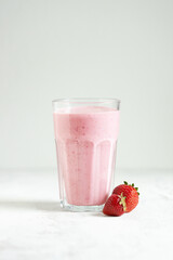 Strawberry smoothie in the glass on white table.