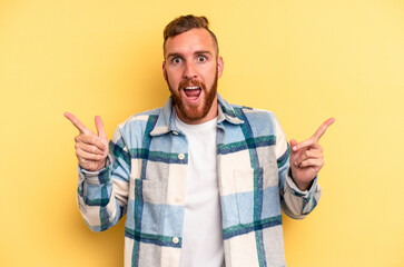 Young caucasian man isolated on yellow background pointing to different copy spaces, choosing one of them, showing with finger.
