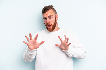 Young caucasian man isolated on blue background rejecting someone showing a gesture of disgust.