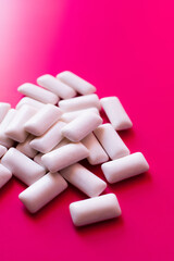 Close up view of white chewing gums on pink background.