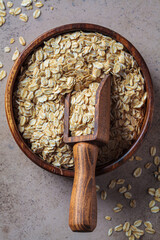 Raw dry oatmeal in wooden bowl, dark background.