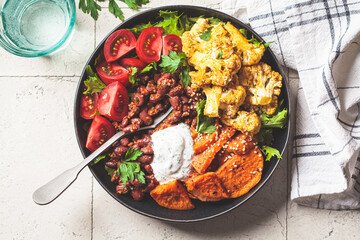 Baked vegetables buddha bowl. Sweet potato, cauliflower, tomato and bean salad. Vegan recipe.