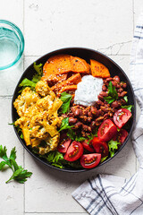 Baked vegetables buddha bowl. Sweet potato, cauliflower, tomato and bean salad. Vegan recipe.